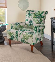 a green and white chair sitting in a living room next to a table with a vase on it