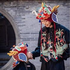 two people in traditional chinese clothing standing next to each other with horns on their heads