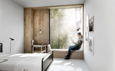 a person sitting on a window sill looking out at the trees outside their bedroom