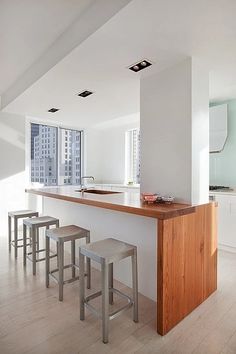 a kitchen with an island and stools next to it in front of a window