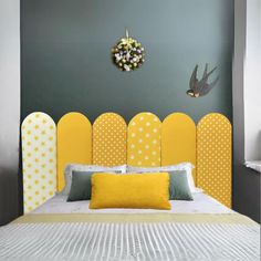 a bed with yellow headboard and pillows next to a clock on the wall above it