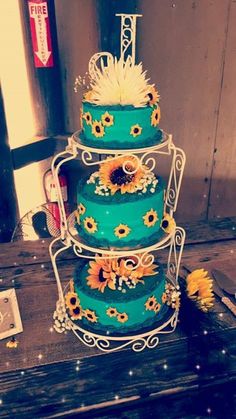 a three tiered cake with sunflowers on the top and bottom is blue