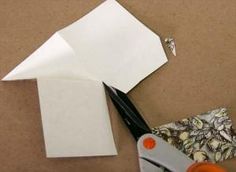 scissors and some paper on a table with other items to make it look like an origami bird