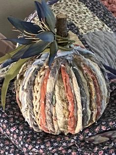 a patchwork pumpkin sitting on top of a bed next to a flowery pillow