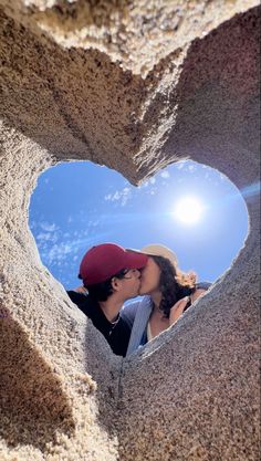 a man and woman kissing in the shape of a heart with sun shining through it