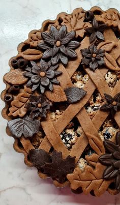 a pie is decorated with chocolate leaves and flowers