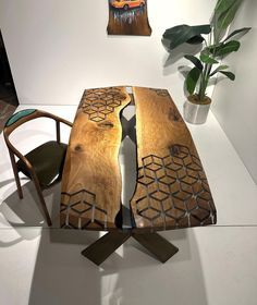 a wooden table sitting on top of a white floor next to a chair and potted plant