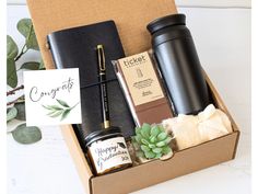 an open gift box containing two coffee mugs, a notepad and some condiments