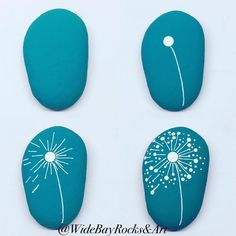 three painted rocks with dandelions on them, one blue and the other white