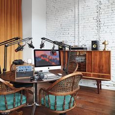 a desk with two chairs and a computer on top of it in front of a brick wall