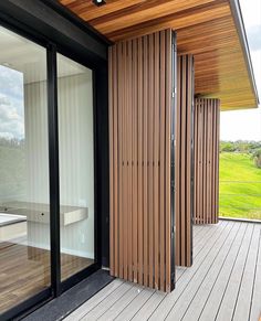 an outdoor deck with sliding glass doors and wood slats on the side of it