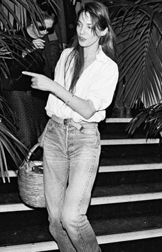 a black and white photo of a woman standing on some steps with her hand in her pocket