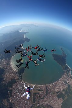 several people are flying in the air with their parachutes over a large body of water