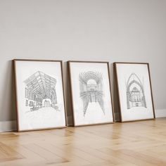 three framed drawings sitting on top of a hard wood floor