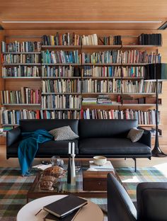 a living room filled with furniture and bookshelves full of bookcases next to a coffee table