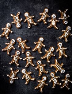 ginger cookies decorated with icing in the shape of skeletons on a black background, top view