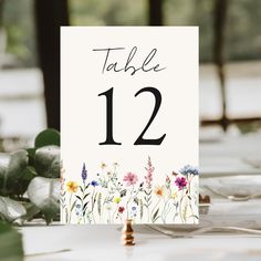 a table number with flowers and greenery on it