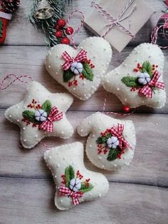 four white christmas ornaments with bows and bells hanging from them on a wooden table next to other decorations