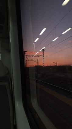 the sun is setting behind some power lines as seen through a window on a train