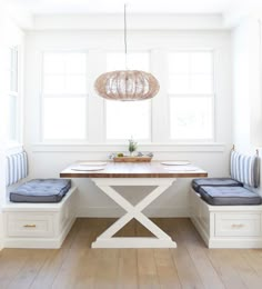 a white table with two benches and a light fixture hanging over it's head