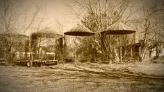 sepia photograph of old grain silos and hay bails in an abandoned country setting