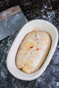 an uncooked bread in a bowl next to a knife