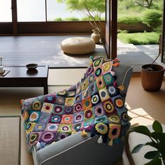 a crocheted granny blanket on a chair in front of a large window