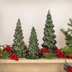 three small christmas trees sitting on top of a mantle