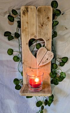 a candle is lit in front of a wooden sculpture with leaves and vines surrounding it