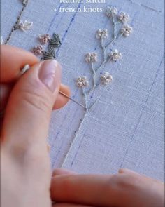 someone is stitching flowers on a piece of fabric