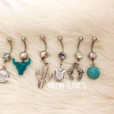 six pairs of dangling belly rings with different designs and colors, including an elephant, giraffe, cactus, and bird