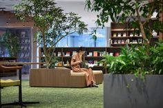 a woman sitting on a couch in front of a book shelf