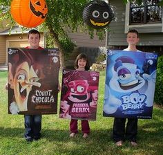 three children holding up posters in front of their house with halloween decorations hanging from the trees