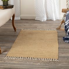 a rug with fringes on the floor next to a chair