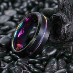 a colorful ring sitting on top of black rocks next to a tree trunk and rock pile