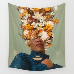 a woman with flowers on her head in front of a wall tapestry