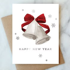 a white card with a red ribbon and a bell on it that says happy new year