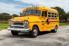 an old yellow school bus parked on the side of the road in front of a fence