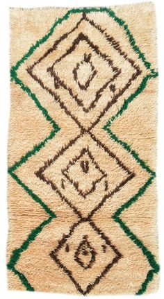 a beige rug with green and brown designs on it's sides, in the shape of diamonds