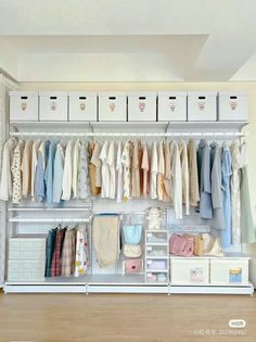 an organized closet with clothes hanging on the wall and storage bins for baby's clothing