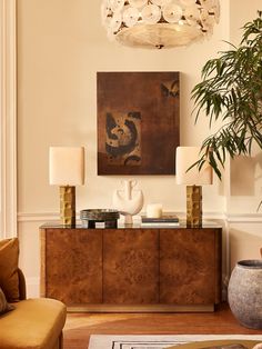 a living room filled with furniture and a large painting on the wall above it's sideboard