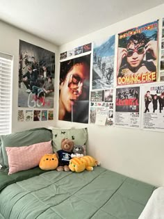 a bedroom with posters on the wall and stuffed animals on the bed in front of it