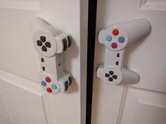 two video game controllers are on the door handle and one is white with multicolored buttons