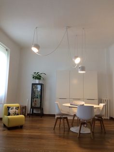 a dining room table and chairs with lights hanging from the ceiling