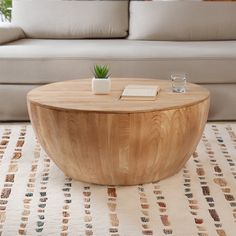 a wooden table sitting on top of a rug in front of a couch and coffee table