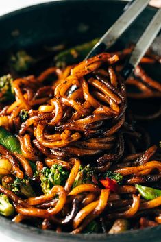 a bowl filled with noodles and broccoli on top of a table next to a fork