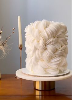 a white cake sitting on top of a table next to a candle