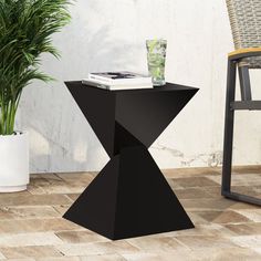 a black table sitting on top of a tiled floor next to a potted plant