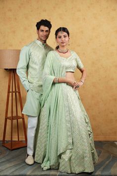 Menswear:- Cotton Silk Kurta in Pastel Green. This Readymade Chinese Collar Neck and Full Sleeve attire is Enhanced with Fancy Buttons, Resham and Sequins Work Available with a Cotton Silk Aligarhi Pant in White and an Art Silk Nehru Jacket in Pastel Green Do note: Footwear shown in the image is for presentation purposes only. Half to one inch may vary in measurement. (Slight variation in actual color vs. image is possible) Lehenga Choli:- Readymade Embroidered Art Silk Lehenga in Pastel Green. Couple Kurta Design, Green Ceremonial Choli With Traditional Drape, Green Couple Outfit, Ceremonial Green Art Silk Lehenga, Fitted Pista Green Sets For Ceremonial Occasions, Pista Green Lehenga With Chikankari Embroidery For Wedding, Ceremonial Raw Silk Sets With Dupatta, Pista Green Wedding Dupatta With Motifs, Ceremonial Lehenga With Resham Embroidery For Eid