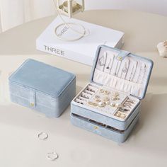 an open blue jewelry box sitting on top of a table next to other jewelry items